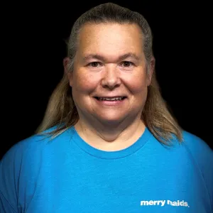 kim is wearing a blue merry maids tshirt standing in front of a black photo backdrop